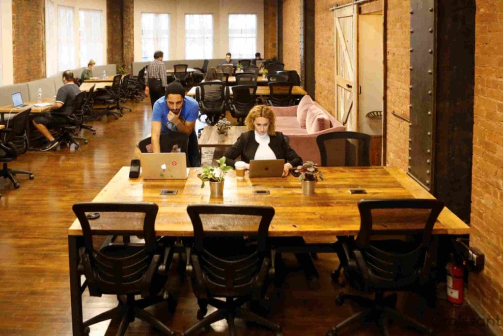 A spacious coworking office filled with individuals focused on their laptops, fostering collaboration and productivity.