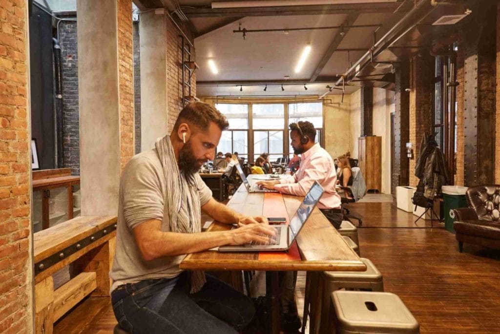A focused man seated at a table with his laptop, representing the dynamic atmosphere of NYC coworking spaces for freelancers.