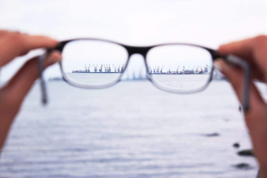 A person displays a pair of glasses against a city backdrop, symbolizing clarity amidst the chaos of multitasking.