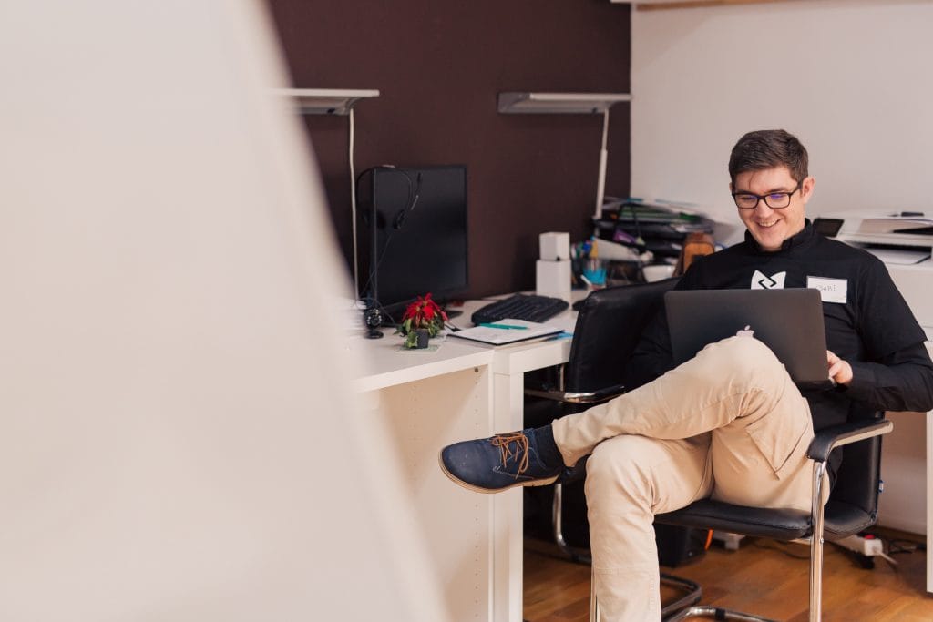 A man seated at a desk with a laptop, concentrating on enhancing employee motivation in a remote work environment.