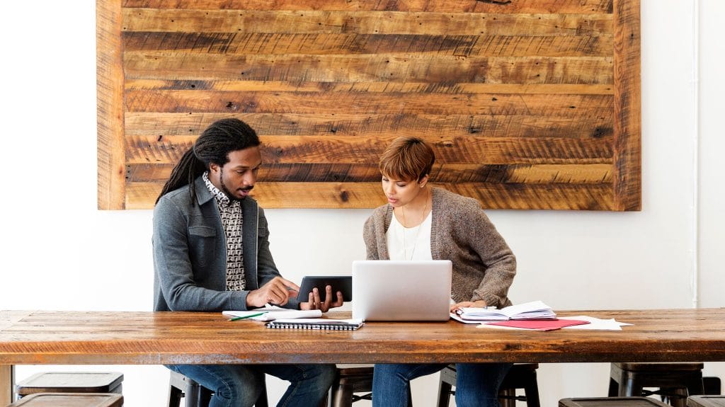 Two professionals seated at a table with a laptop, focused on boosting productivity in a private office space.