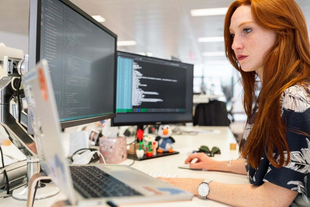 A woman engaged with her computer in an office setting, highlighting the importance of efficiency in saving time and money.