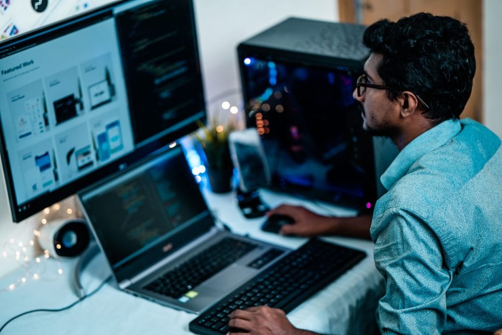 A man seated at a desk with two computers, symbolizing effective methods for businesses to save time and money.