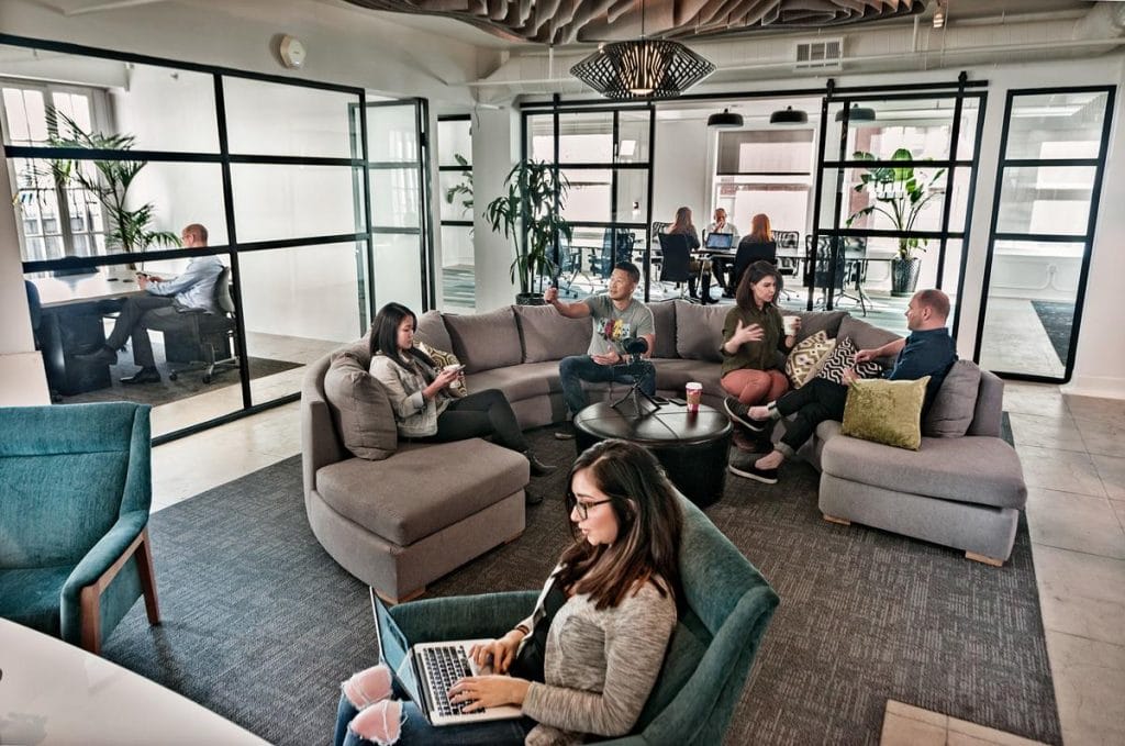 Individuals comfortably seated in an open office setting, emphasizing a vibrant and interactive coworking space.