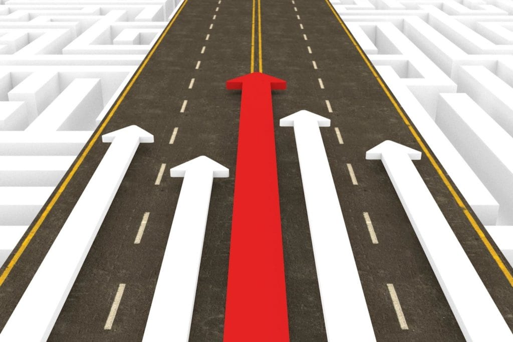 A symbolic image of a road, where several white arrows are joined by a larger red arrow in the center.