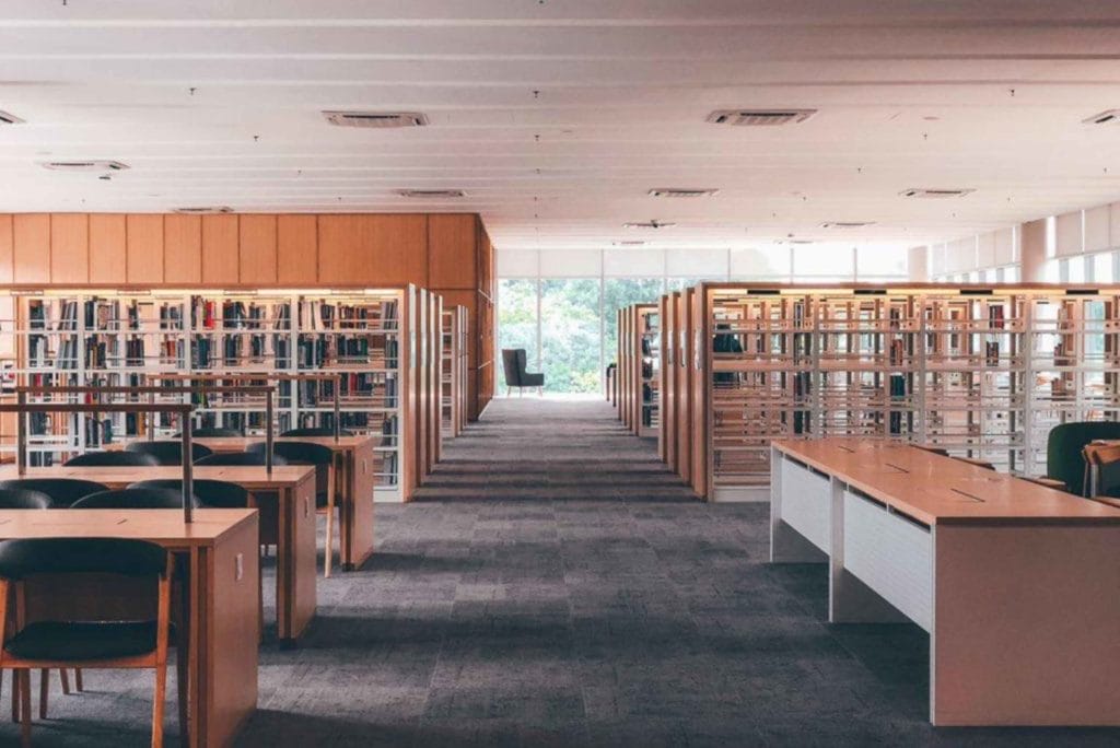 A spacious library filled with bookshelves and tables, ideal for reading and studying in a serene environment.