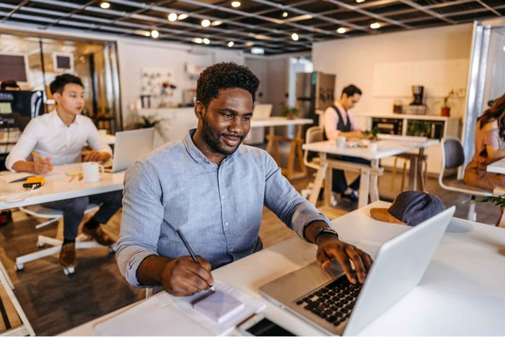 A young professional working on a laptop at a coworking desk, embodying the concept of remote work in a shared office space.