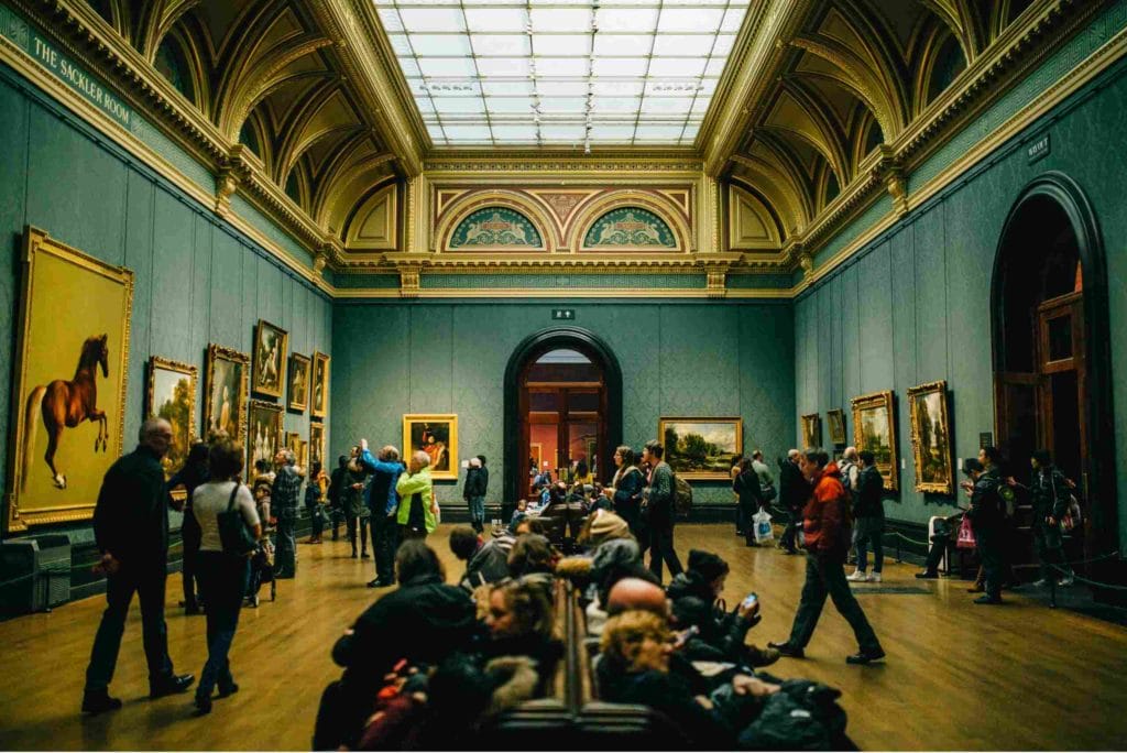 People gathered in an art museum, seated and immersed in the artistic displays that surround them.