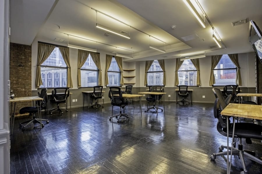 An expansive room filled with desks and chairs, ideal for office work and group discussions.