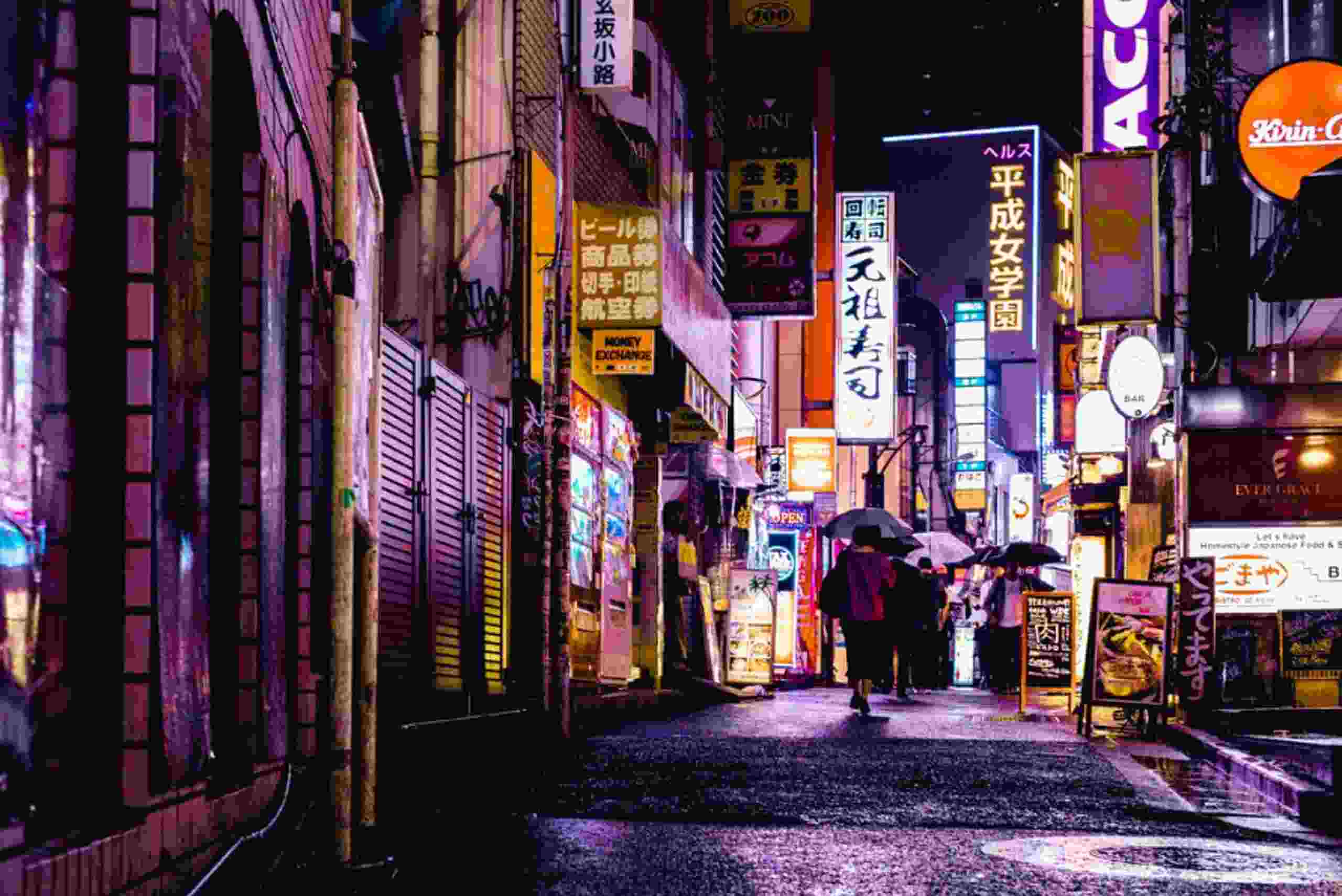 A nighttime view of a Tokyo street, filled with glowing neon signs, highlighting the energy of urban coworking spaces.
