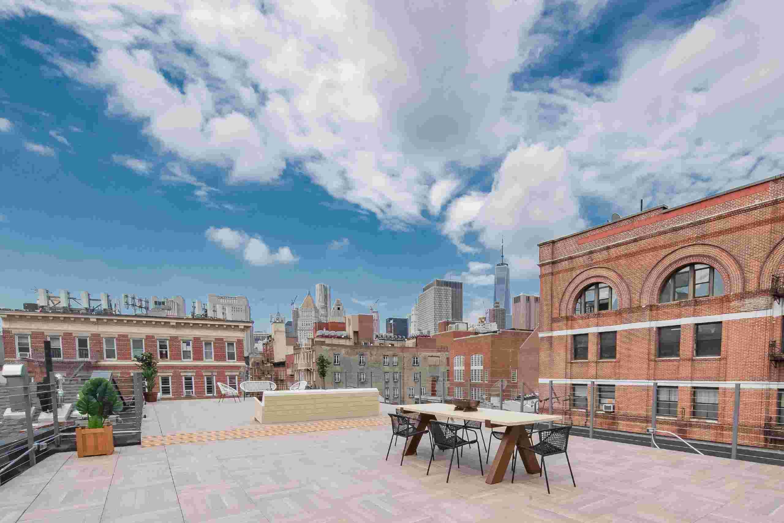 The rooftop patio of a New York loft, ideal for gatherings, featuring a panoramic view of the vibrant Manhattan skyline.