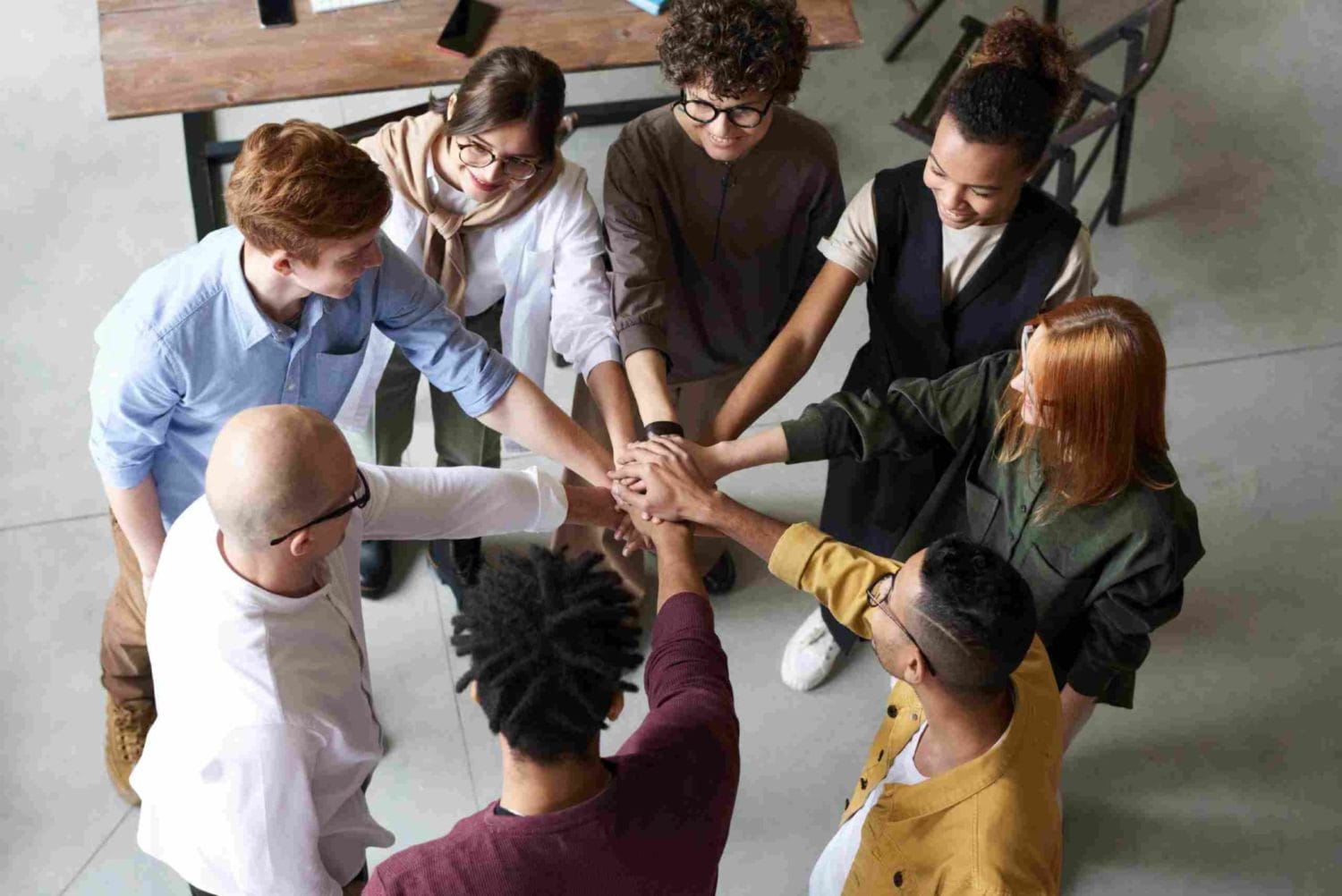 A circle of individuals with linked hands, embodying collaboration and support for racial equity in the workplace.