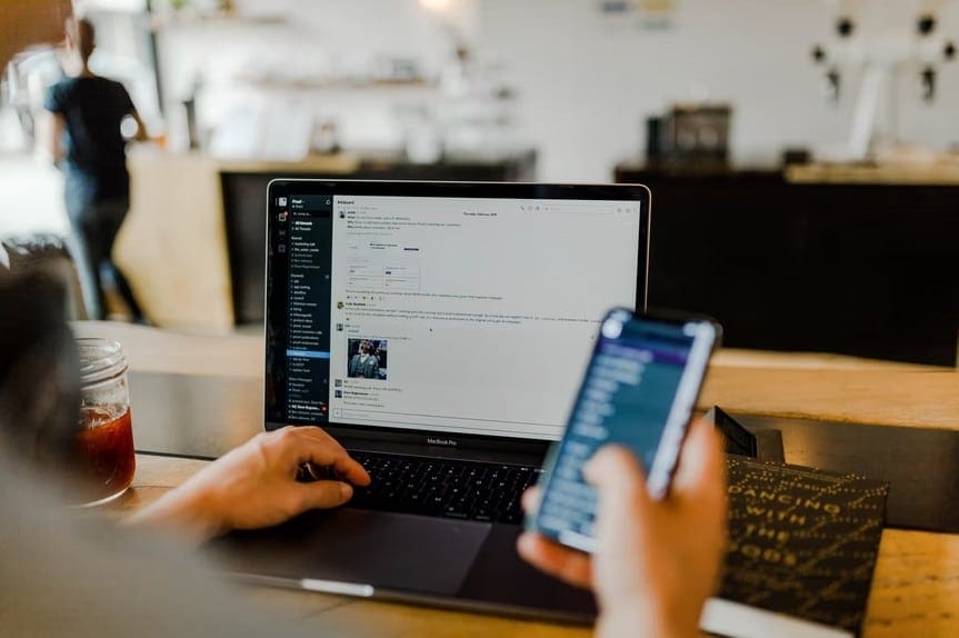 A professional utilizing a laptop and smartphone, demonstrating strategies to enhance workplace efficiency and productivity.