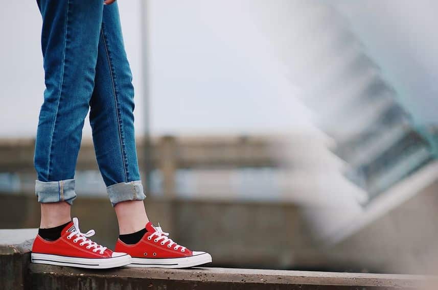 A woman in red sneakers stands confidently on a ledge, embodying the spirit of a digital nomad ready for adventure.