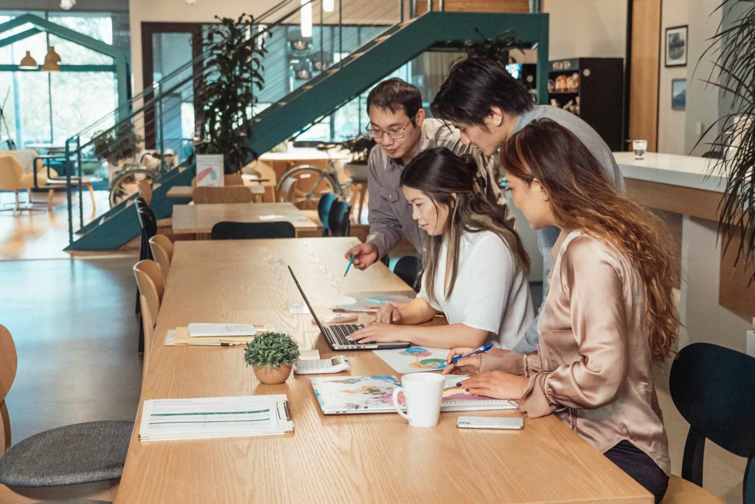 A group of individuals engaged in discussion around a table in a modern coworking office environment.