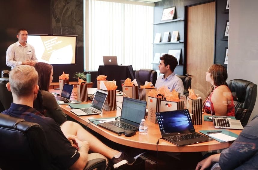 A diverse group of professionals collaborating around a table, each using laptops for a productive meeting.