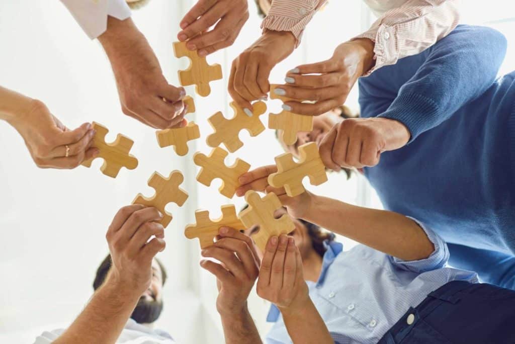 Business professionals collaborating to fit puzzle pieces together, symbolizing teamwork and strategic planning during a retreat.