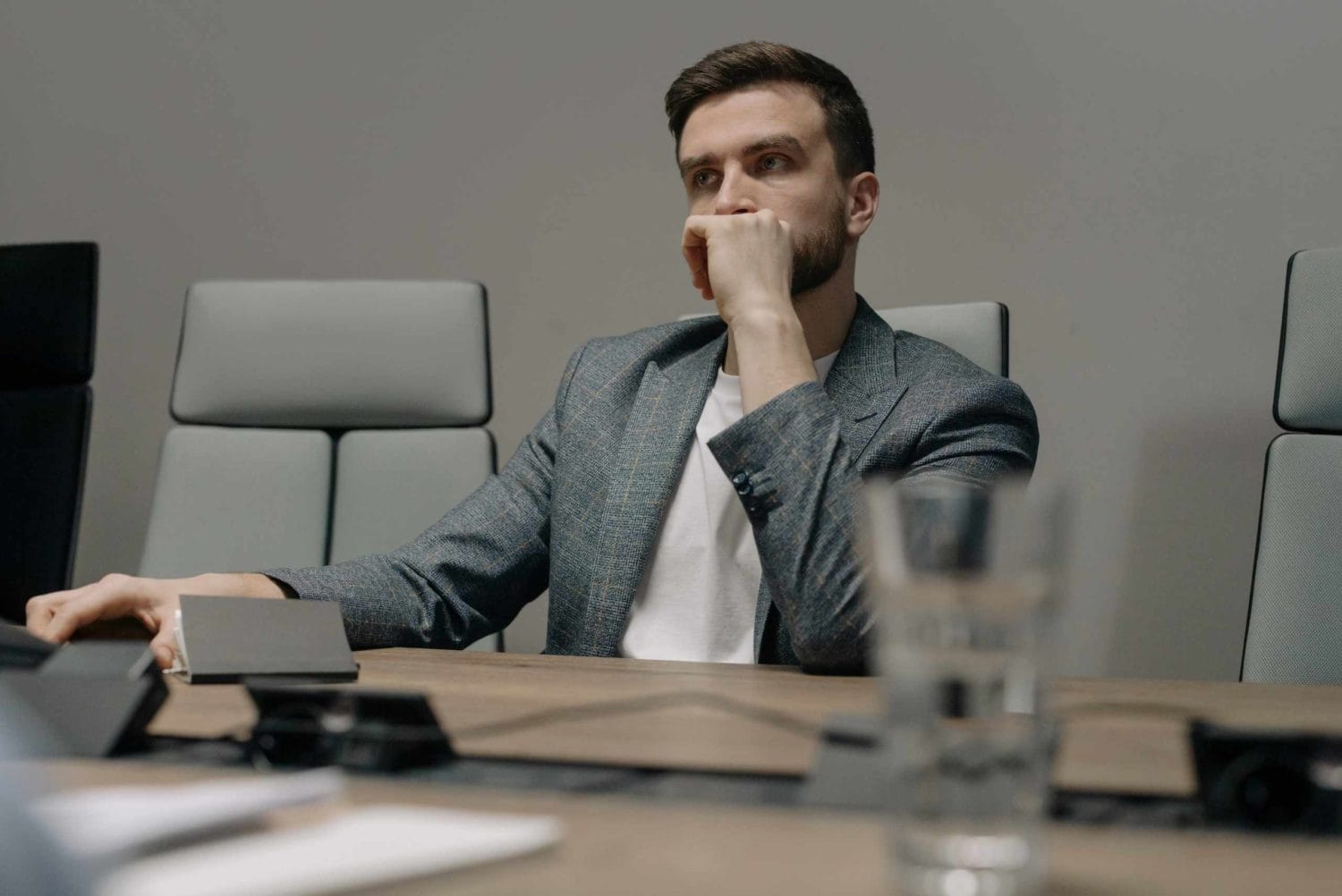 A man deep in thought at a table, hands on his chin, considering various business opportunities for passive income.