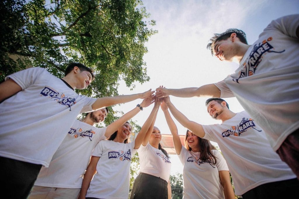 A team of professionals in white shirts holding hands, fostering collaboration during a corporate retreat.