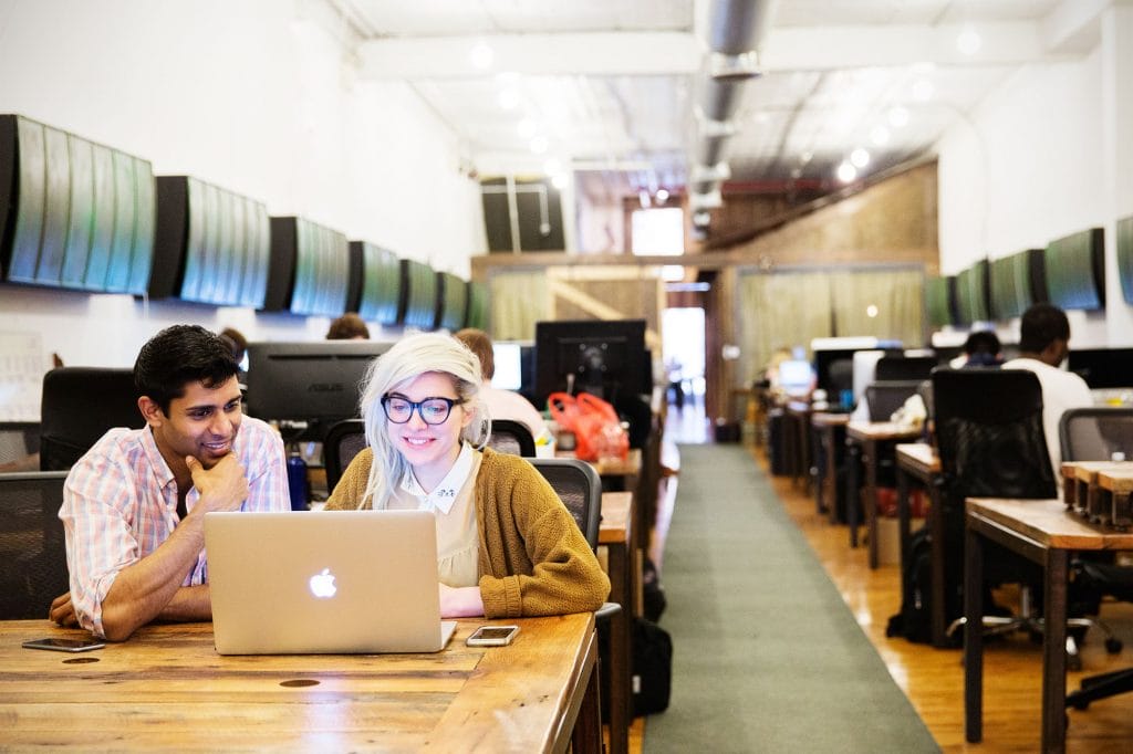 Two people working intently on laptops in a spacious open office, illustrating the dynamic atmosphere of coworking.