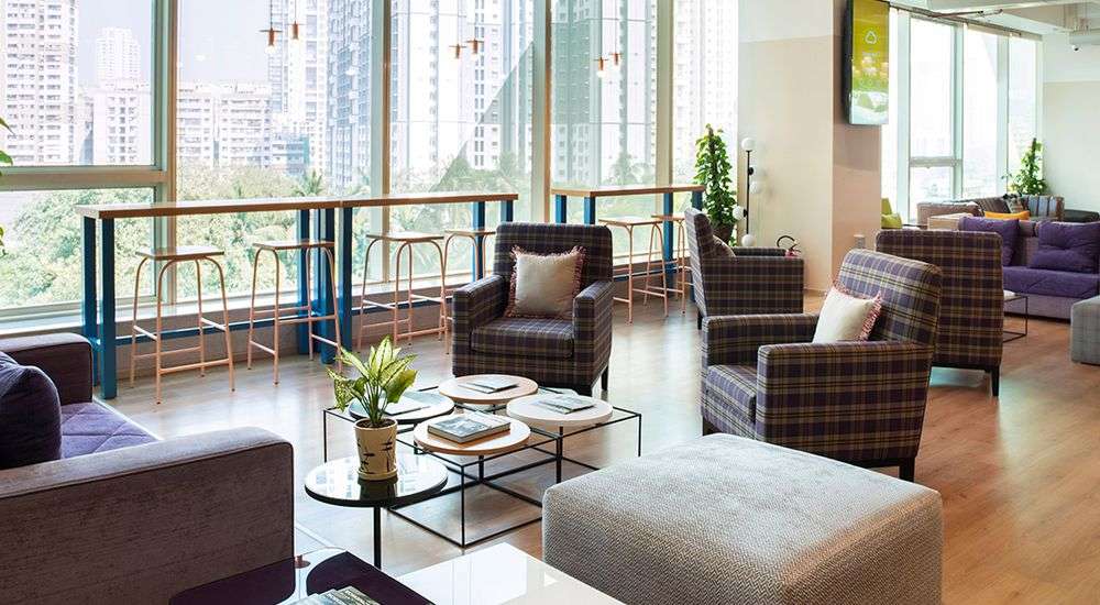 A spacious living room featuring a large window and an array of stylish furniture, creating a welcoming atmosphere.