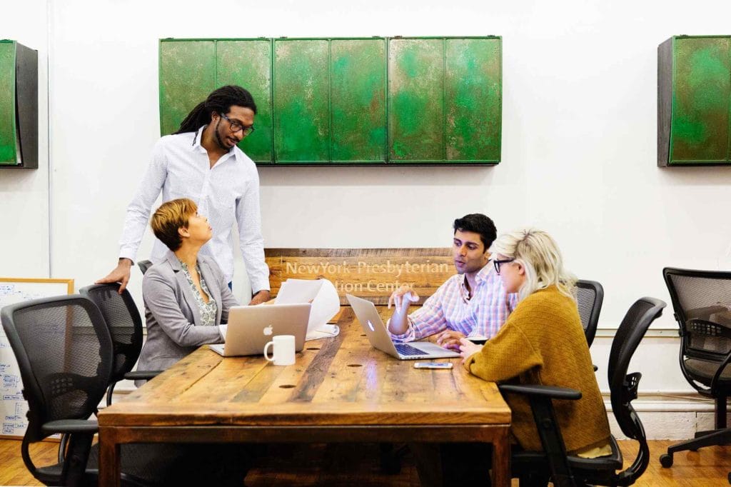 A collaborative scene of individuals seated at a table with laptops, exemplifying a dynamic coworking space.