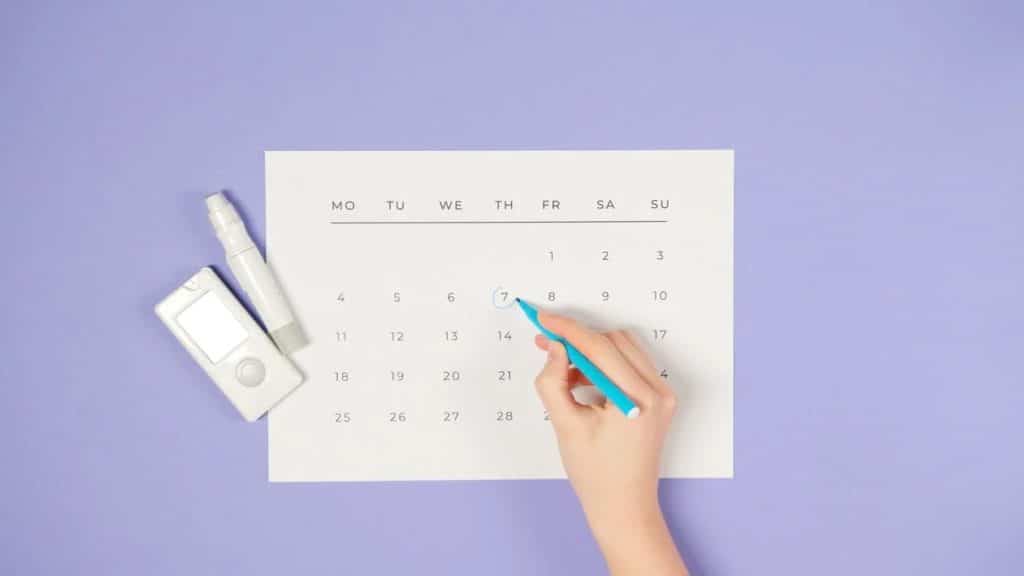 A woman's hand writing on a calendar, symbolizing the planning of online events for a small business.