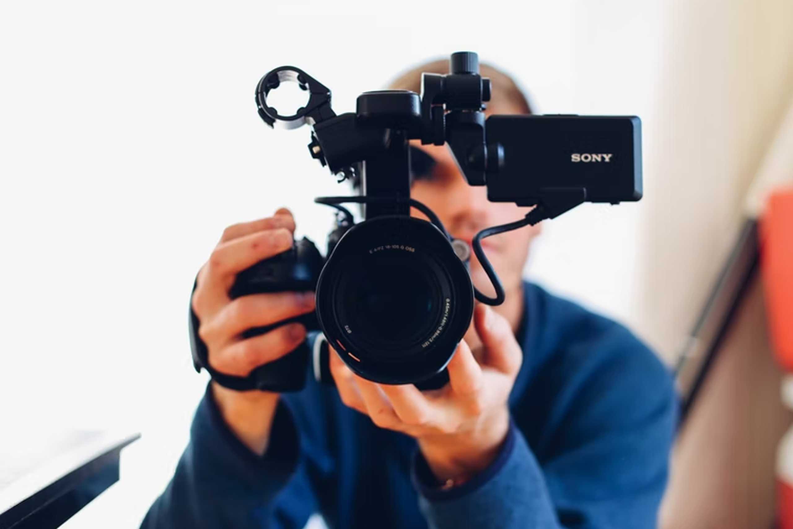 A man captures an image with a camera in front of a computer, showcasing the role of video marketing in small business success.