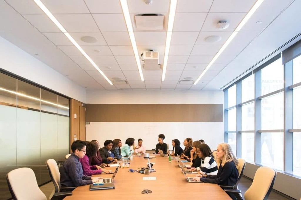 People engaged in discussion around a table in a conference room, showcasing a well-organized office layout.