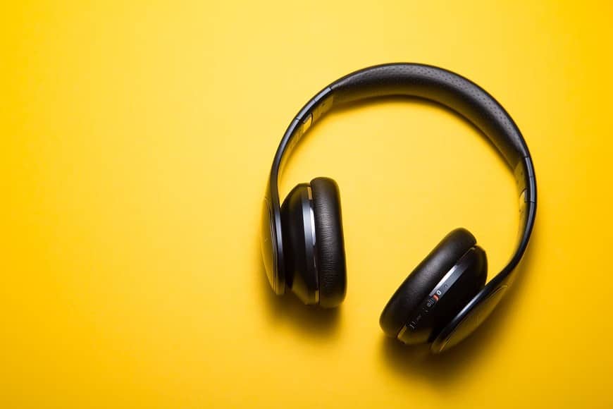 Headphones displayed on a cheerful yellow surface, representing the influence of music on enhancing productivity at work.