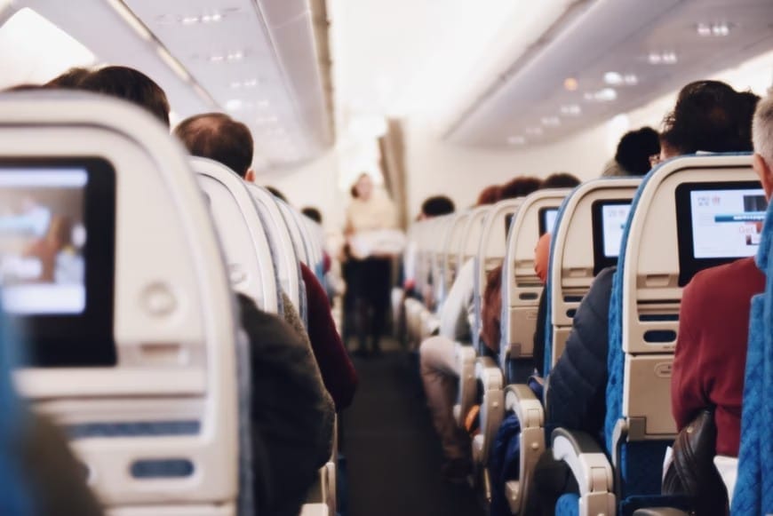 People seated in the aisle of an aircraft, illustrating the concerns of digital nomads due to escalating fuel expenses.