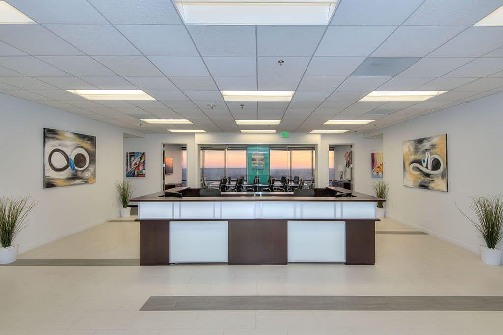 An inviting office space showcasing a reception desk and decorative paintings, ideal for a coworking atmosphere.