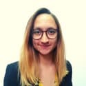 Nina Petrov, smiling while wearing glasses and a professional outfit, featured in a blog about combating virtual meeting fatigue