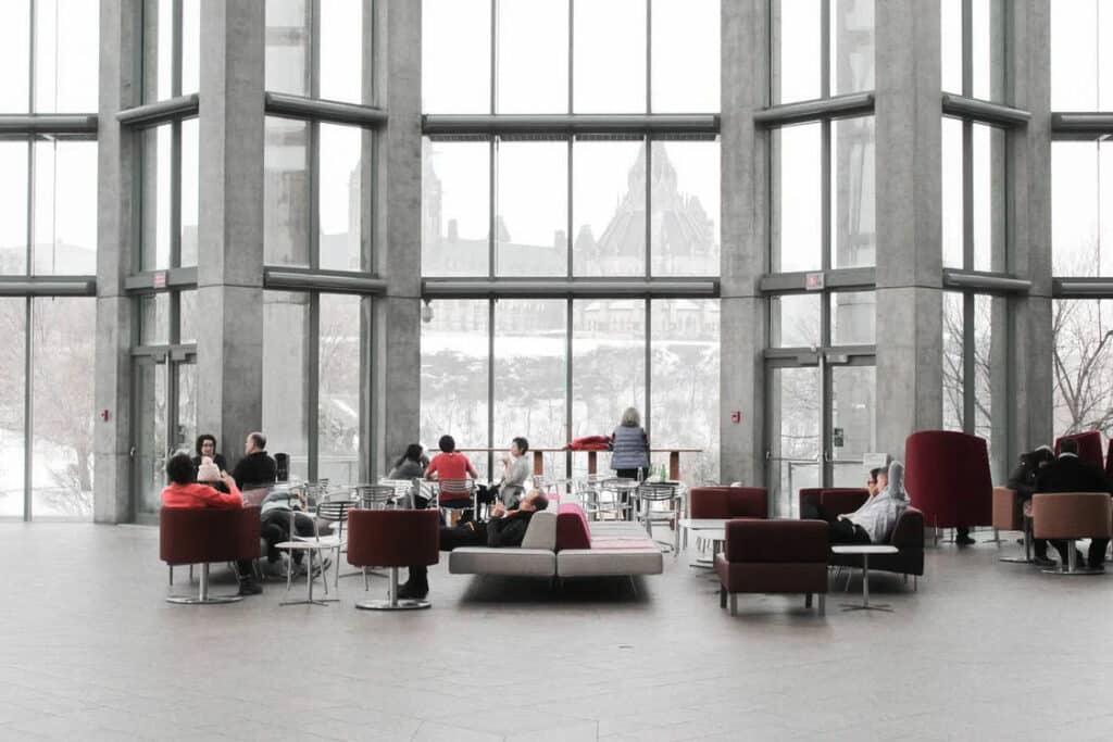Individuals gathered in a bright room with expansive windows, highlighting a vibrant coworking space atmosphere.