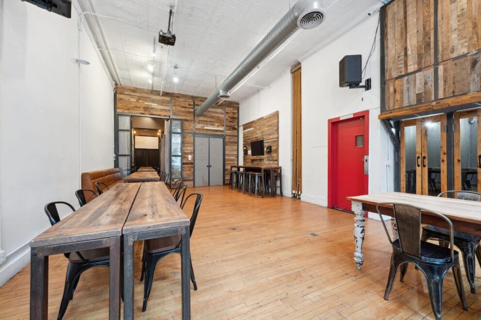 A large room with wooden floors and tables, perfect for hosting corporate events at The Farm Soho.