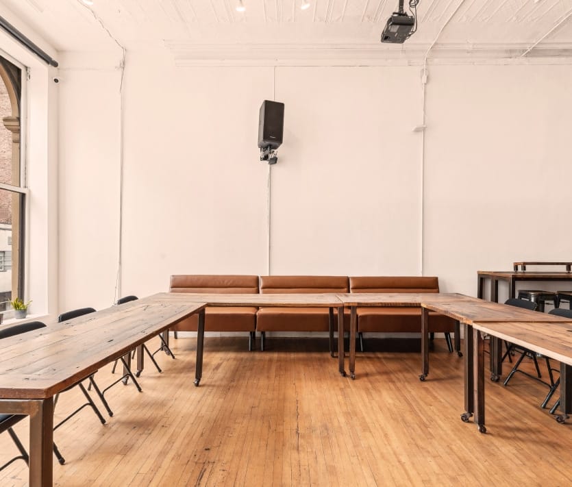 Expansive room showcasing wooden tables and chairs, ideal for gatherings in a loft-style venue.