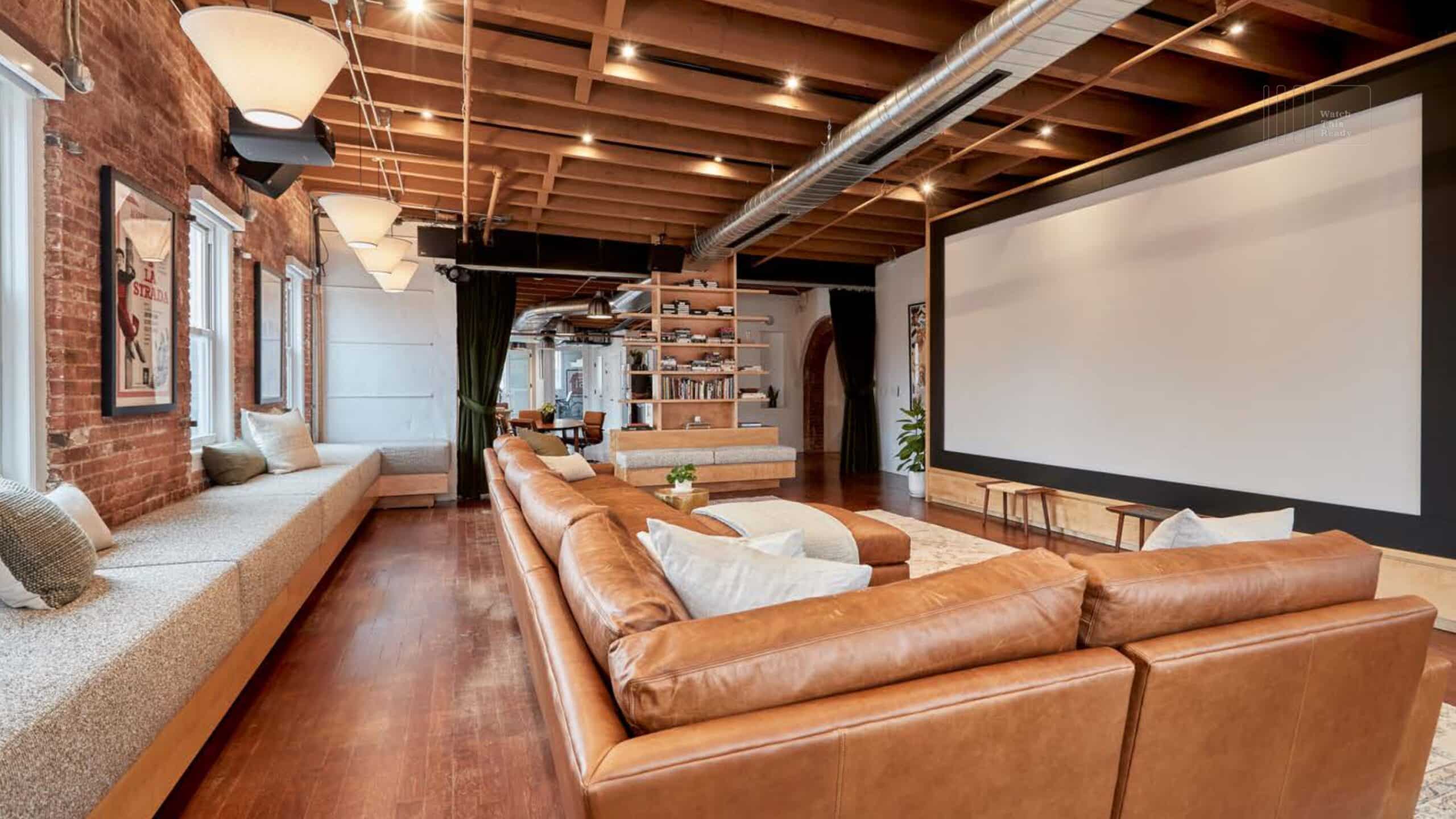 An inviting living room with a modern couch and a projector screen, perfect for gatherings and presentations.