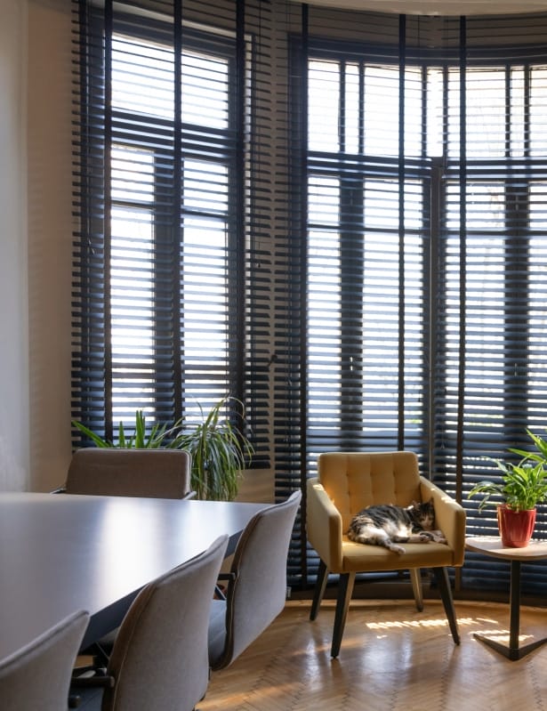 An office space with a table and chairs, complemented by a window with blinds, ideal for a productive work environment.