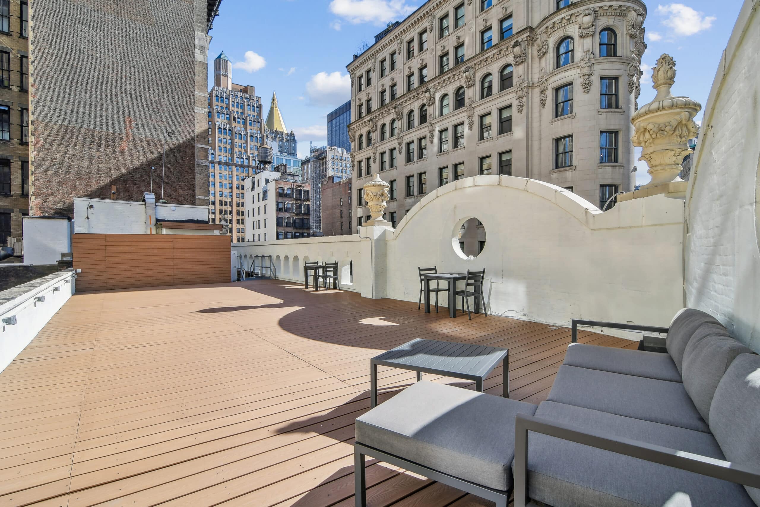  A scenic rooftop patio overlooking the city skyline, featuring comfortable seating and vibrant greenery.