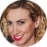 A confident woman with curly hair and striking red lipstick, embodying elegance and charm in her appearance.