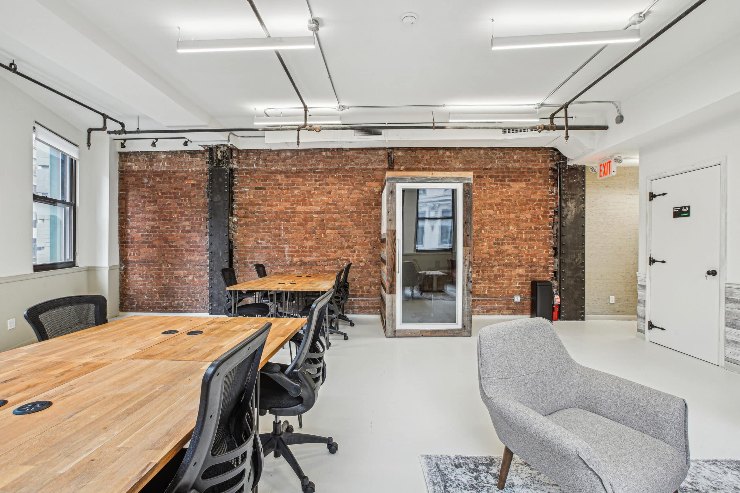 An office interior with a stylish brick wall and comfortable chairs, creating a welcoming atmosphere for productivity.